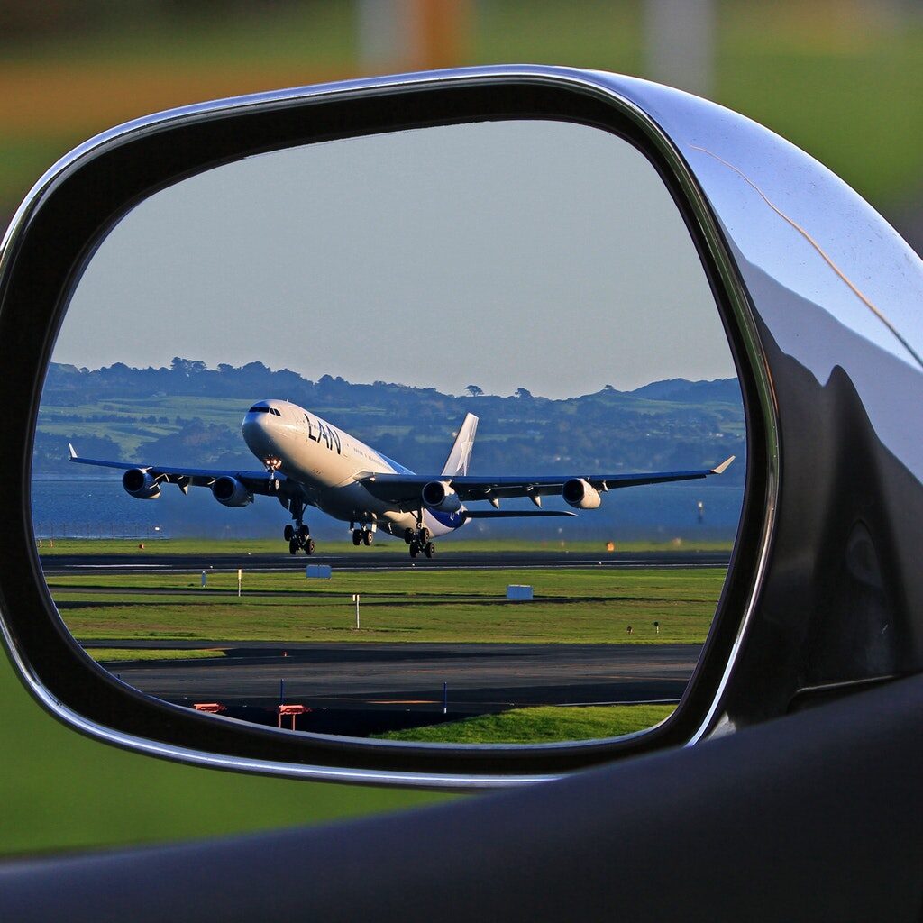 Foto di aereo visto da specchietto retrovisore per trasferimento aeroportuale
